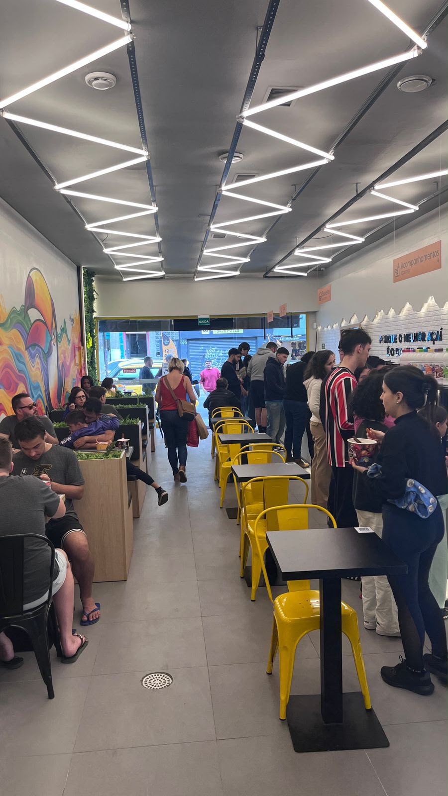 Clientes na nossa loja The Best Açaí em Pinheiros, com mesas e cadeiras amarelas